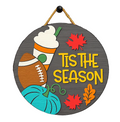 A round hanging wall sign with  the phrase “Tis the Season." The sign features autumn-themed illustrations including a pumpkin, a football, a coffee with whipped cream, red and orange leaves, and a hanging cord. Available in San Antonio TX at DIY Sign Party.